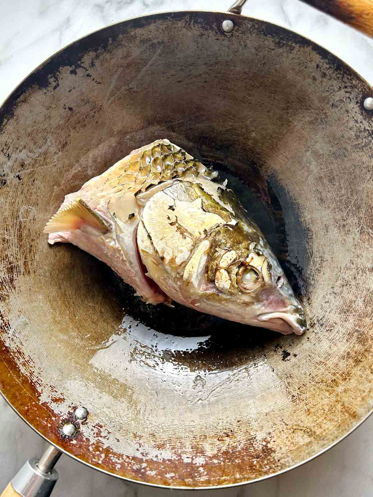 fish head being fried in wok