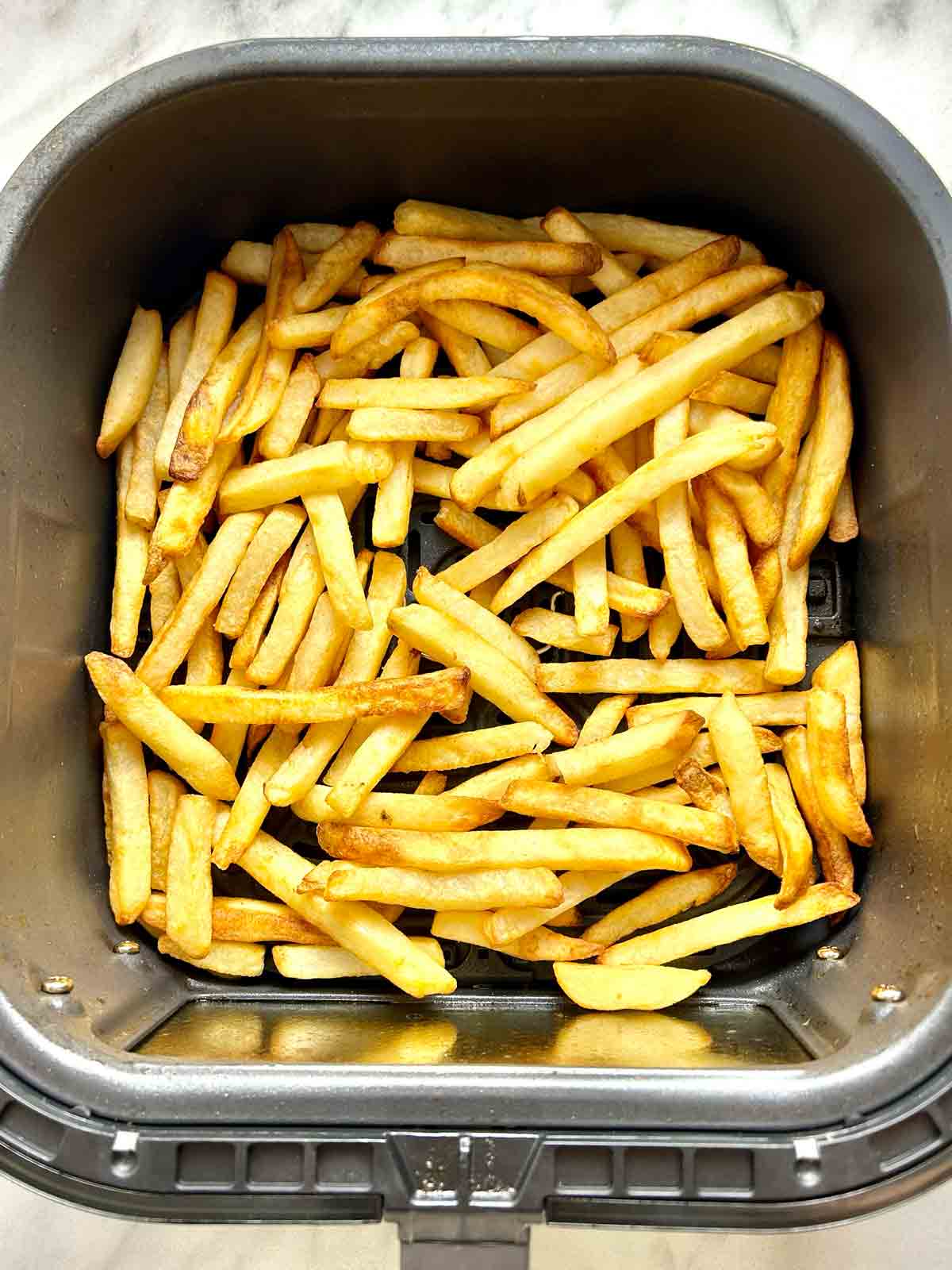 cooked fries in air fryer basket.