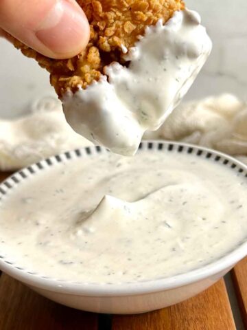 chicken tender being dipped into ranch sauce