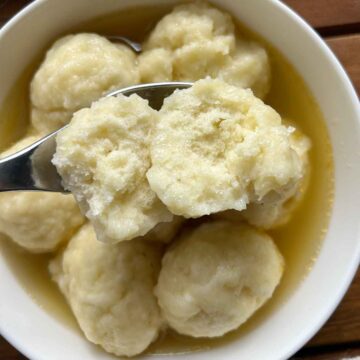 top down view of spoon holding split-open doughboy over bowl of doughboys