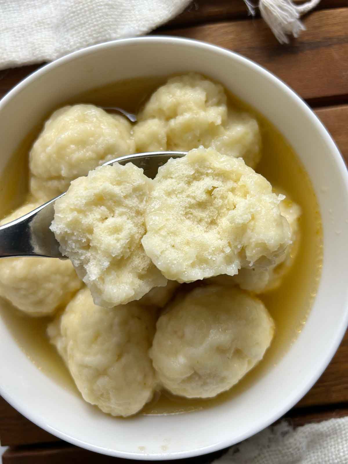 top down view of spoon holding split-open doughboy over bowl of doughboys