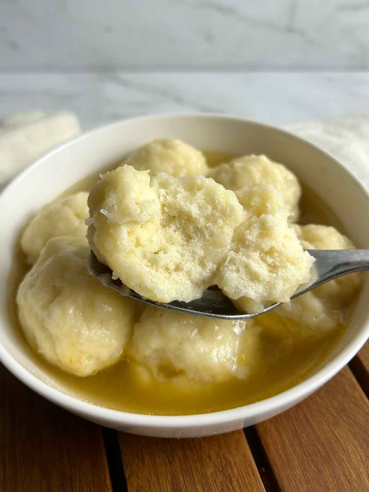 spoon holding split open doughboy over bowl of doughboys