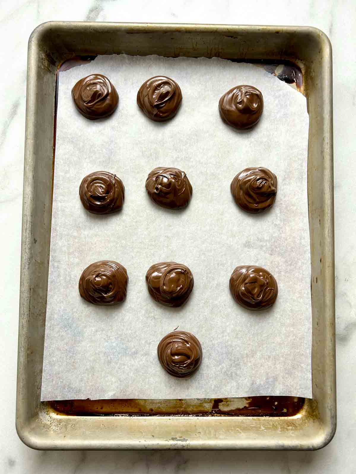 blobs of Nutella portioned out on parchment-lined baking sheet