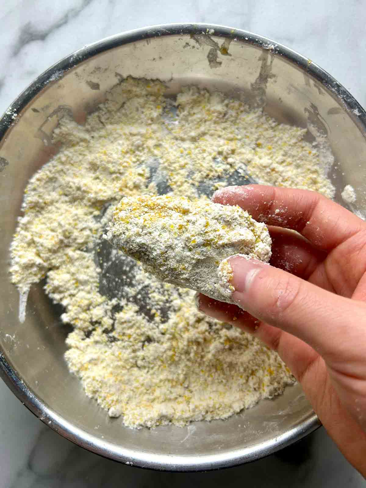 sardine being coated in breading mixture.