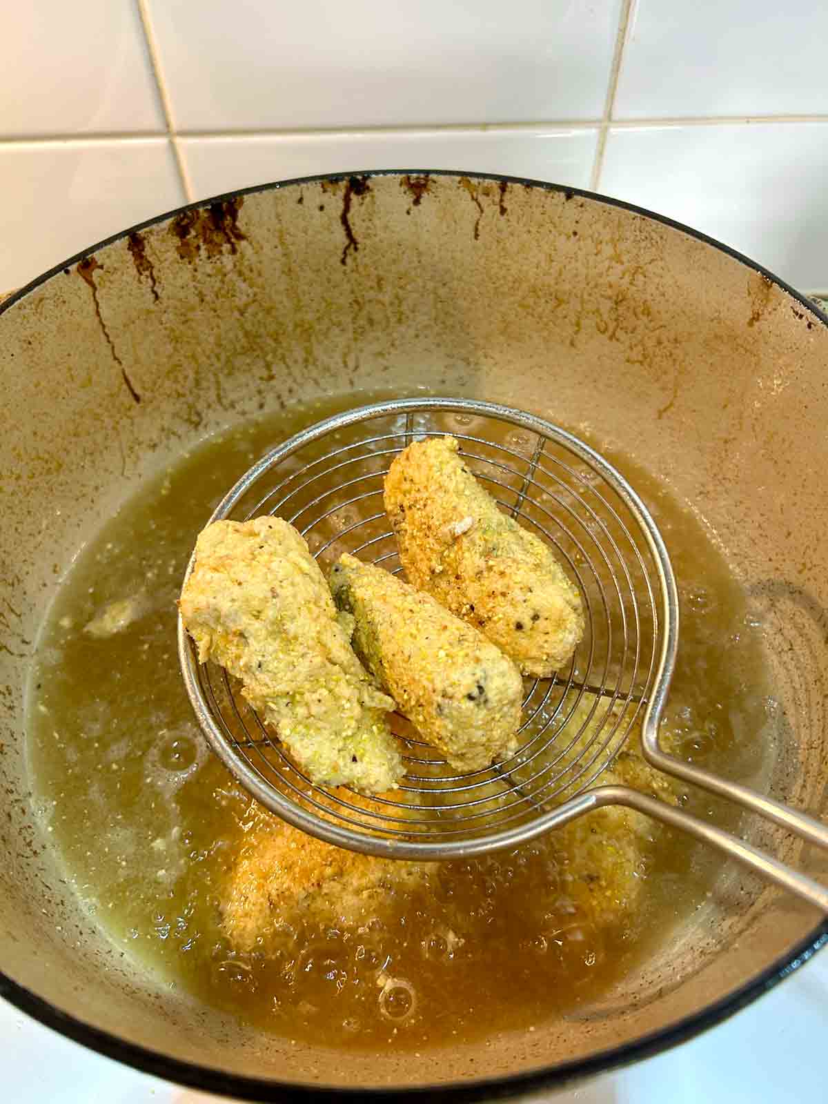 metal spider lifting out fried sardines from hot oil.