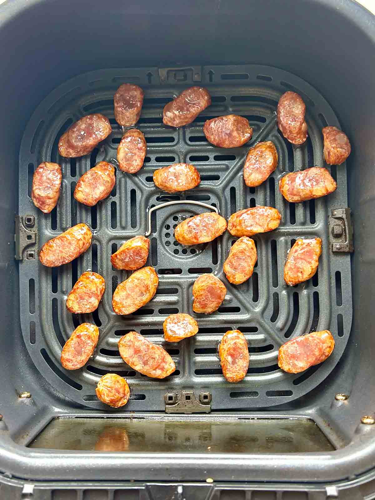 sliced Chinese sausages in air-fryer basket after cooking for 2 minutes.