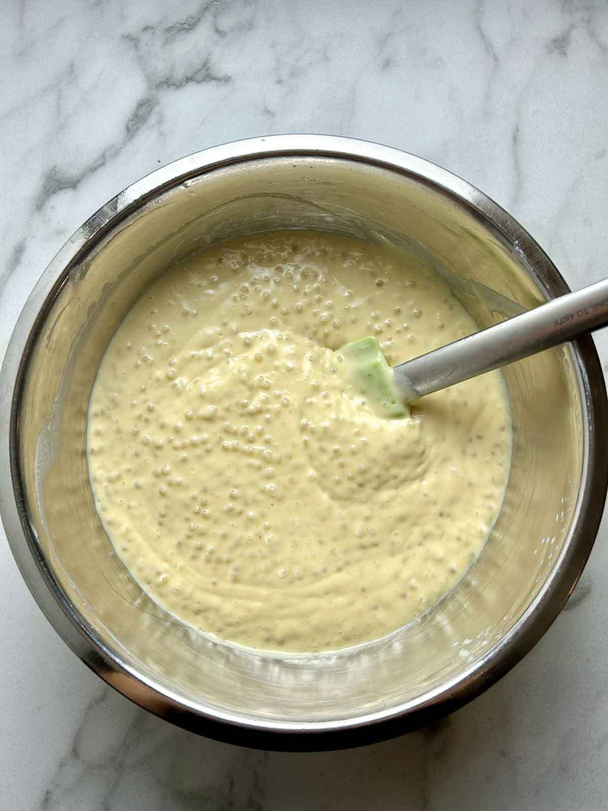 cooked tapioca being mixed with durian mixture in bowl.