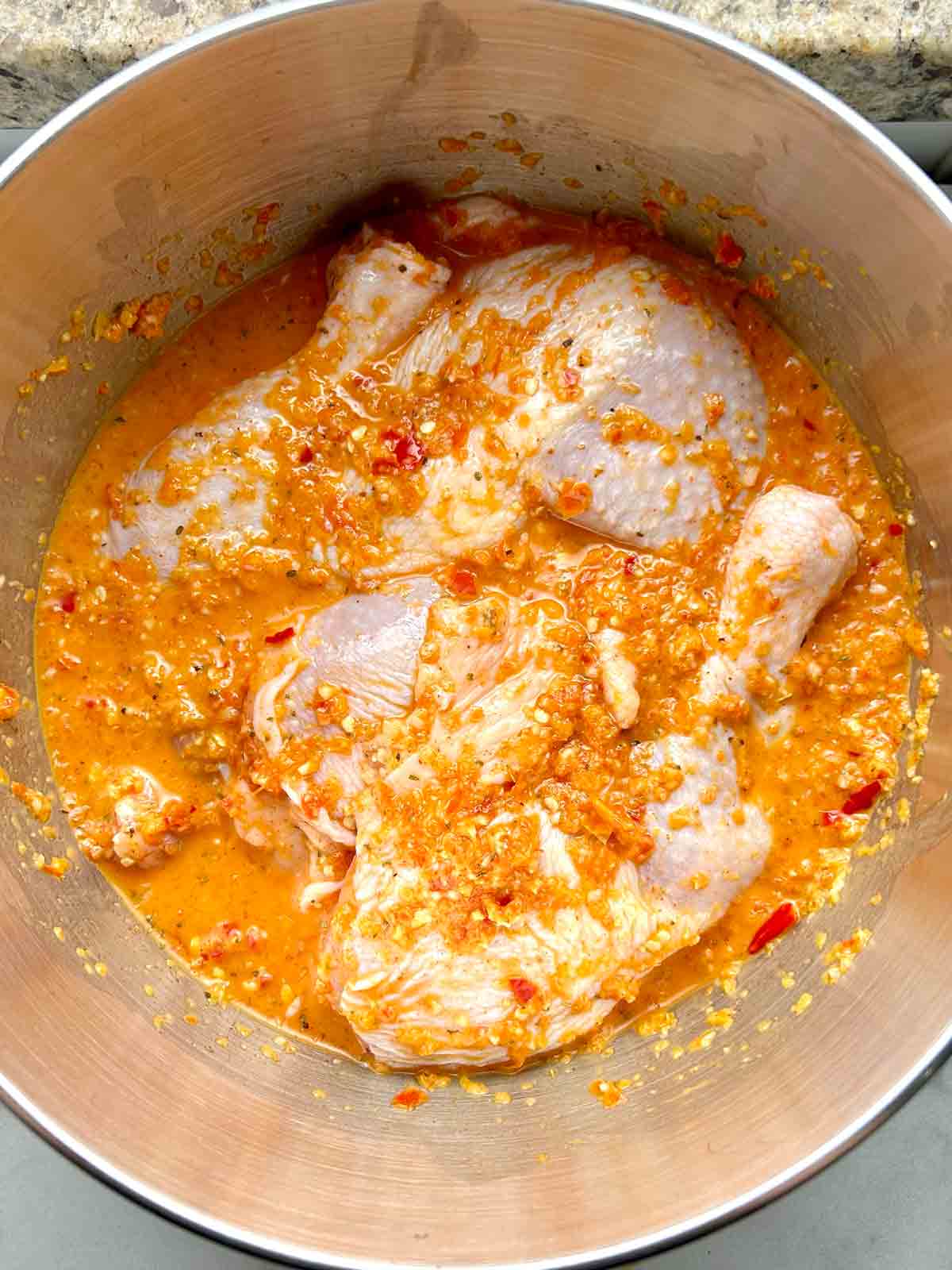 chicken legs being marinated in Nando's peri peri sauce.