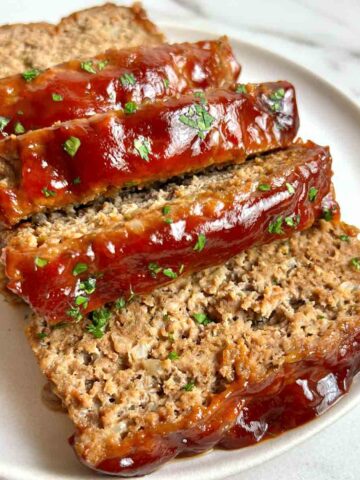 meatloaf cut into thick slices on plate; parsley sprinkled on top.