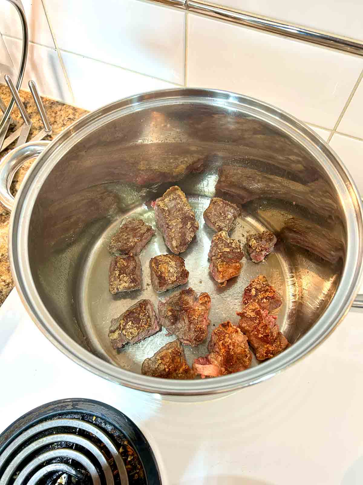 beef cubes being browned in pot.