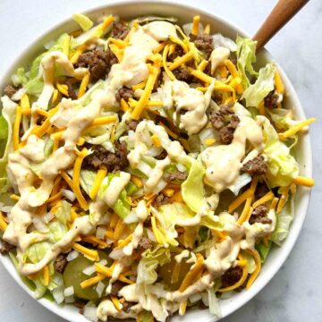 big mac salad in bowl with sauce drizzled on top.