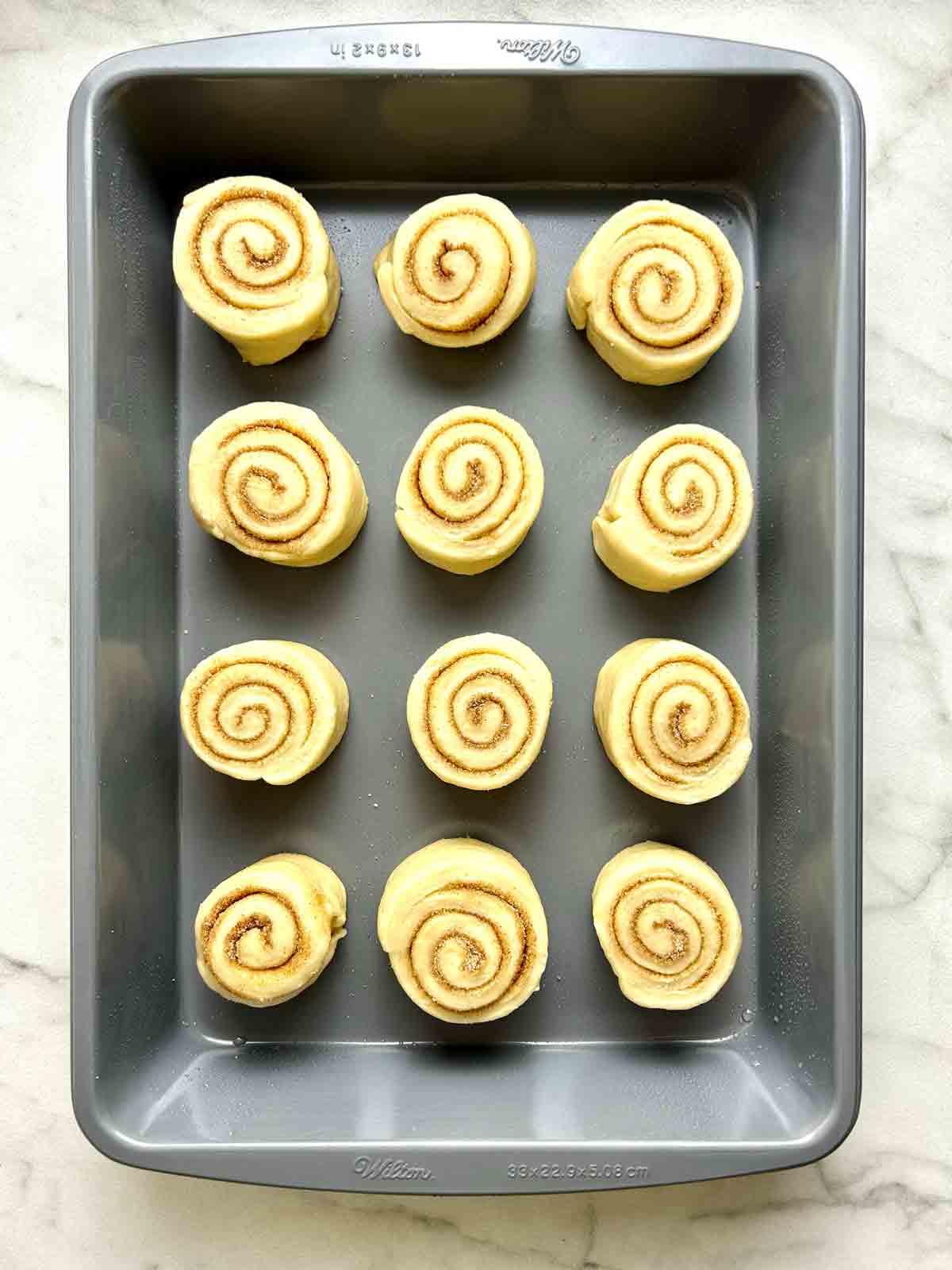 cinnamon rolls arranged in baking pan.