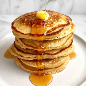 syrup being poured over stack of oatmeal pancakes.