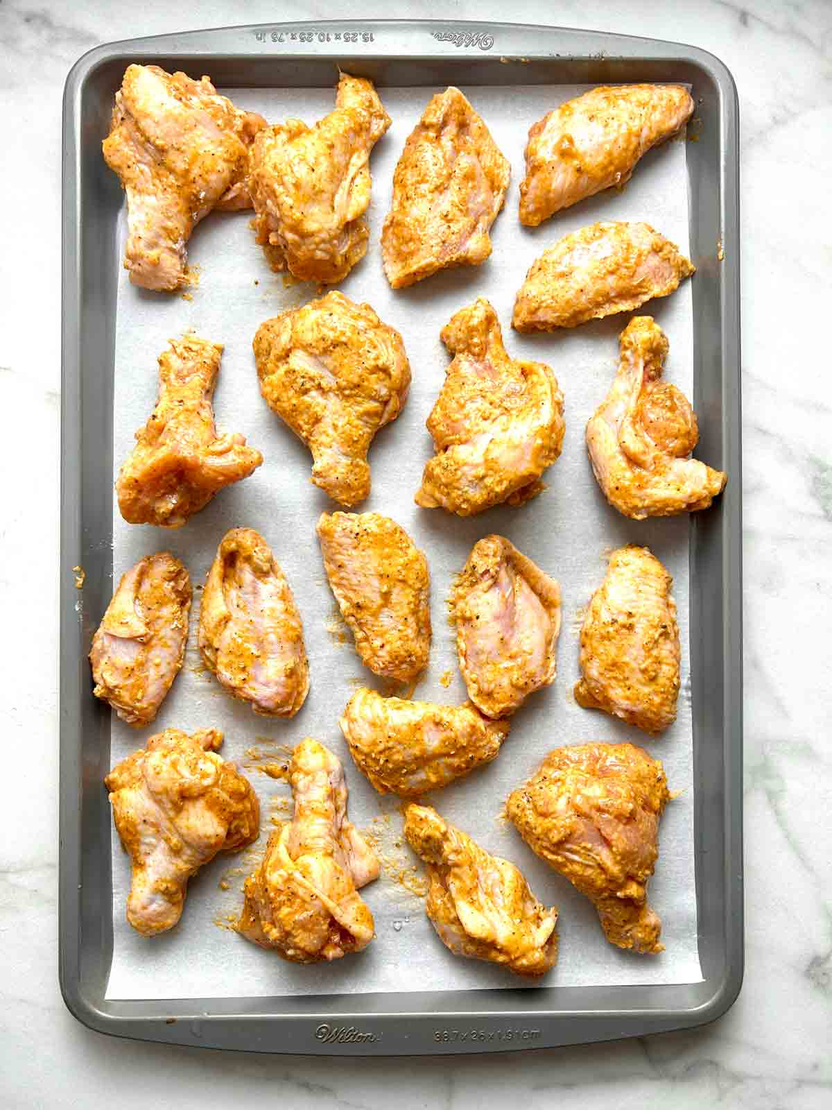 chicken wings arranged on parchment-lined baking sheet.