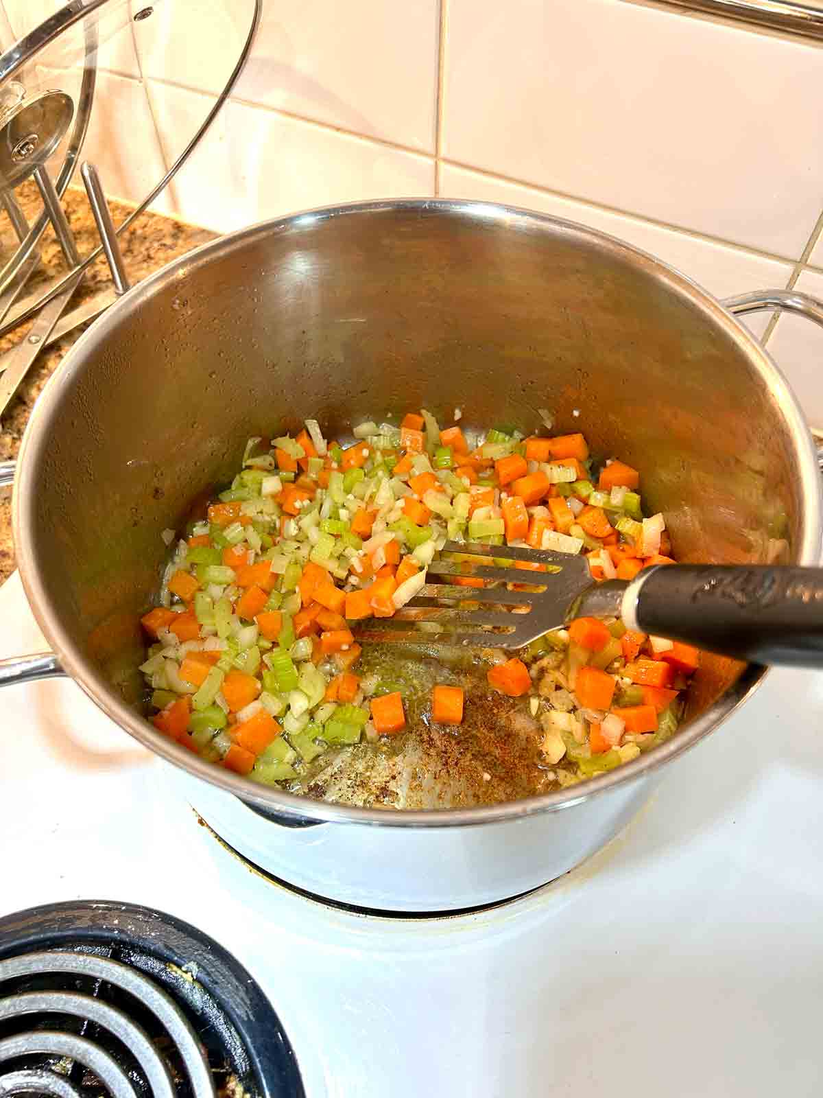 carrots, onions, celery, and garlic being cooked in pot.
