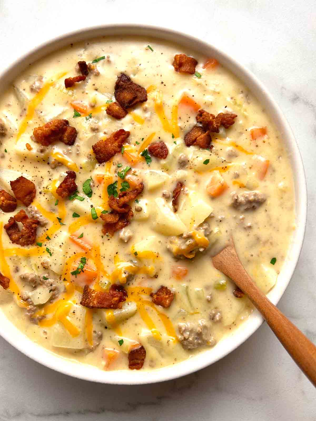 close up of cheeseburger soup in bowl with bacon bits on top.