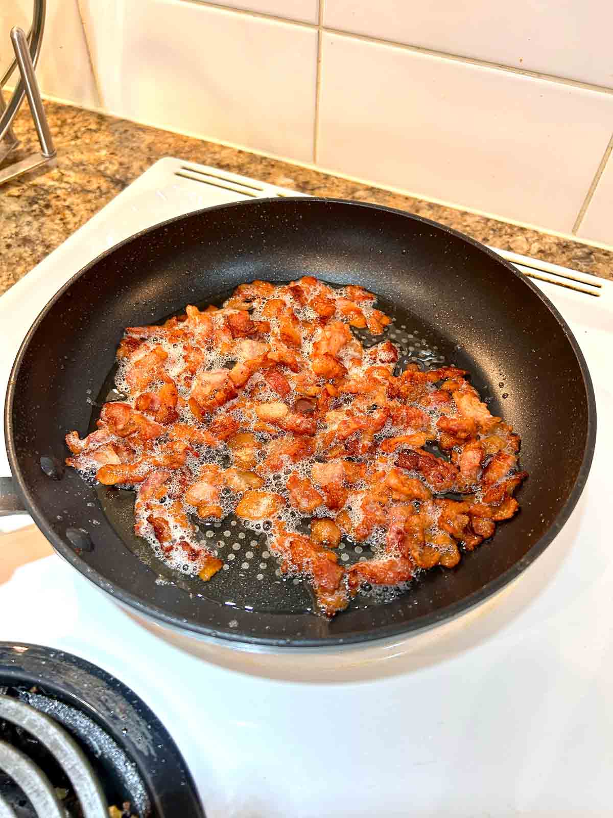 bacon being crisped in nonstick pan.