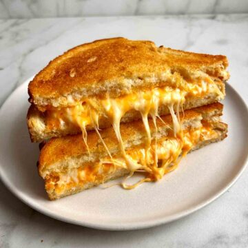grilled cheese cut in half and stacked on top of each other showing the melted cheese.