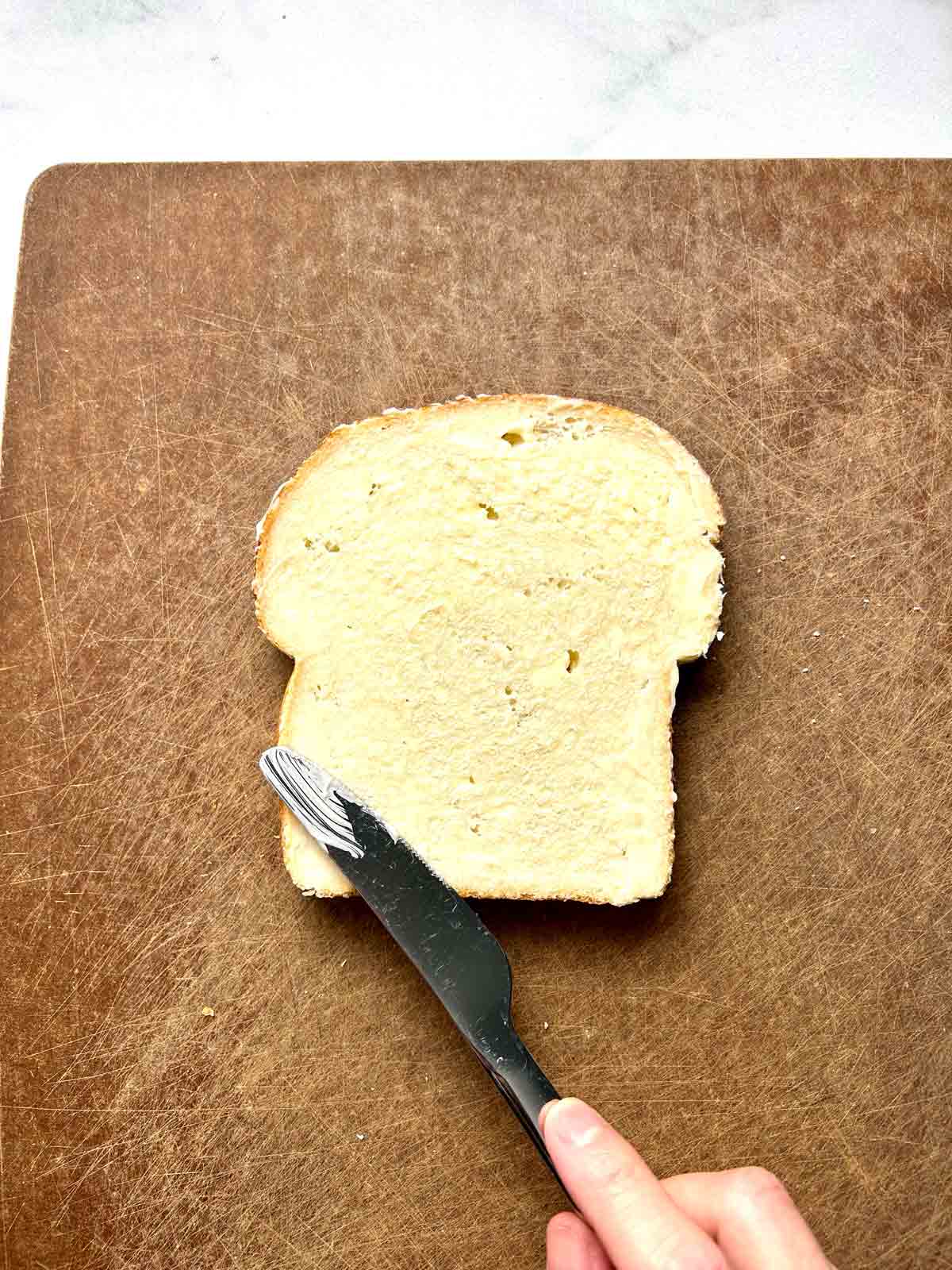 butter being spread on bread slice.