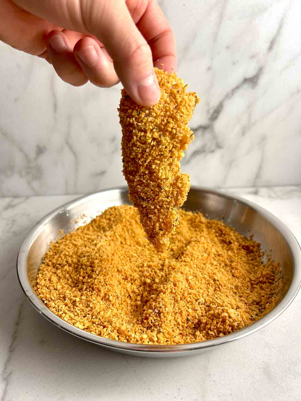 coating chicken tender in toasted breadcrumbs