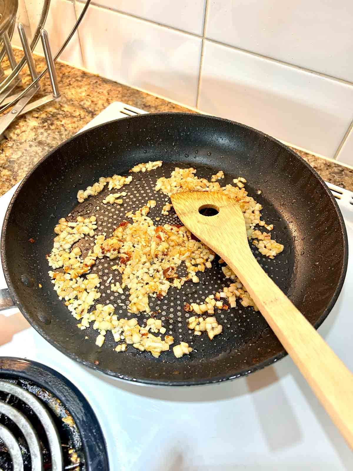 onions and garlic being sautรฉed in pan.