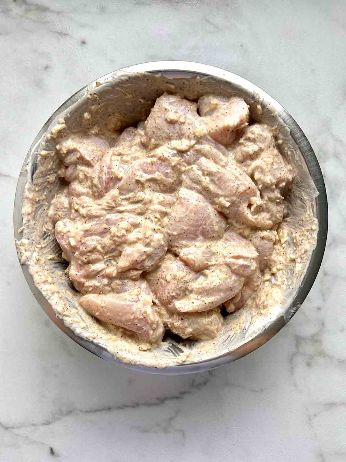 chicken being marinated in bowl.