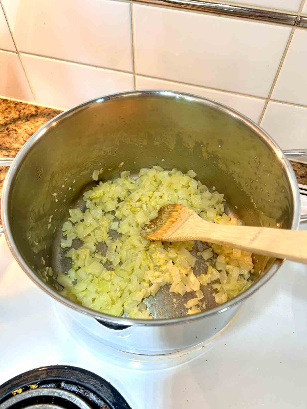 onions, garlic, and ginger being cooked in pot.