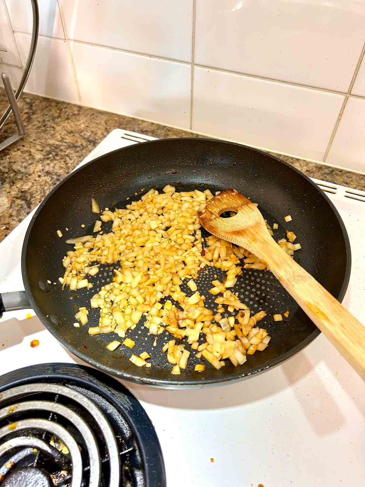 onions and garlic being sautรฉed in pan.