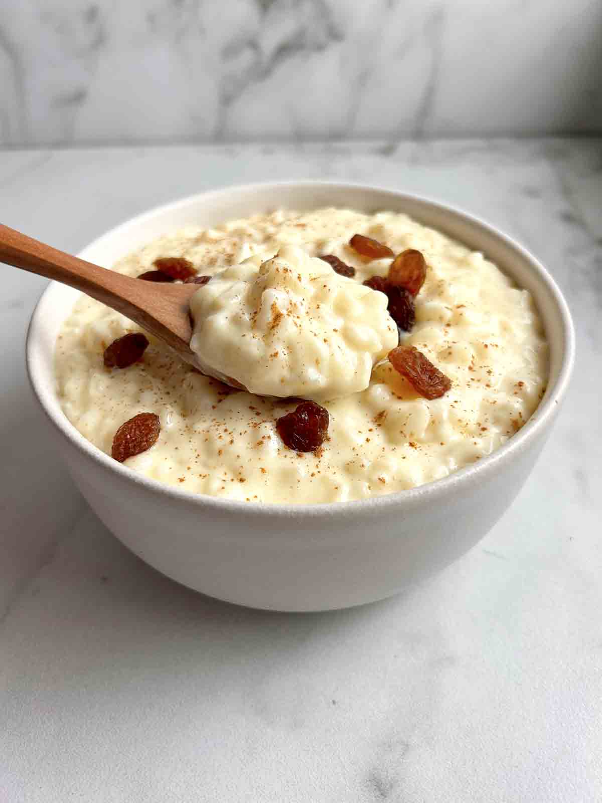 bowl of rice pudding with raisins and cinnamon on top.