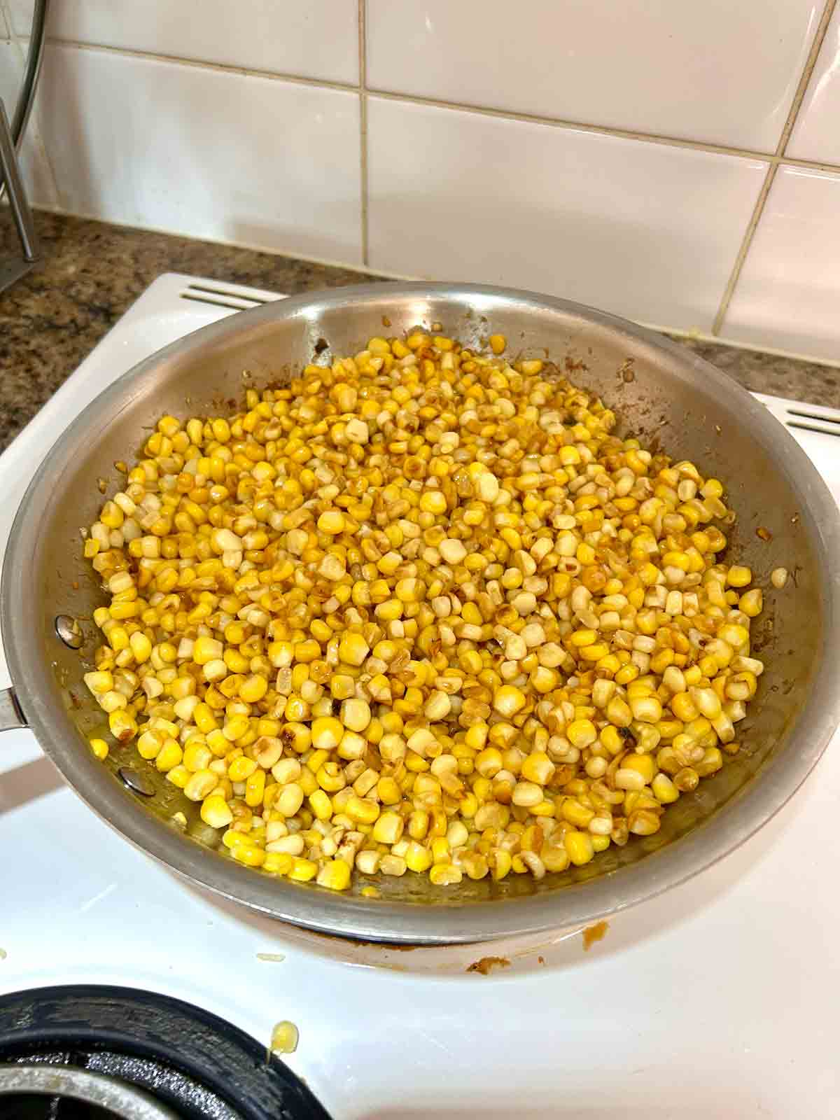 corn kernels being sautรฉed in skillet.
