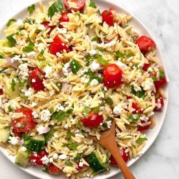 plate of orzo salad with spoon sticking out of it.
