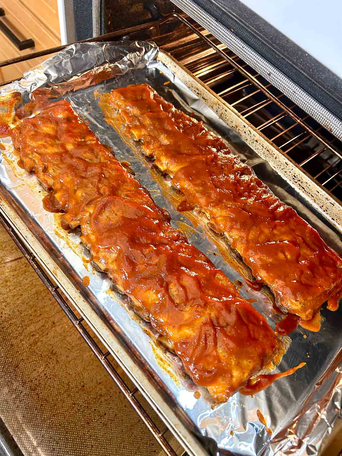 racks of ribs being slathered with barbecue sauce.