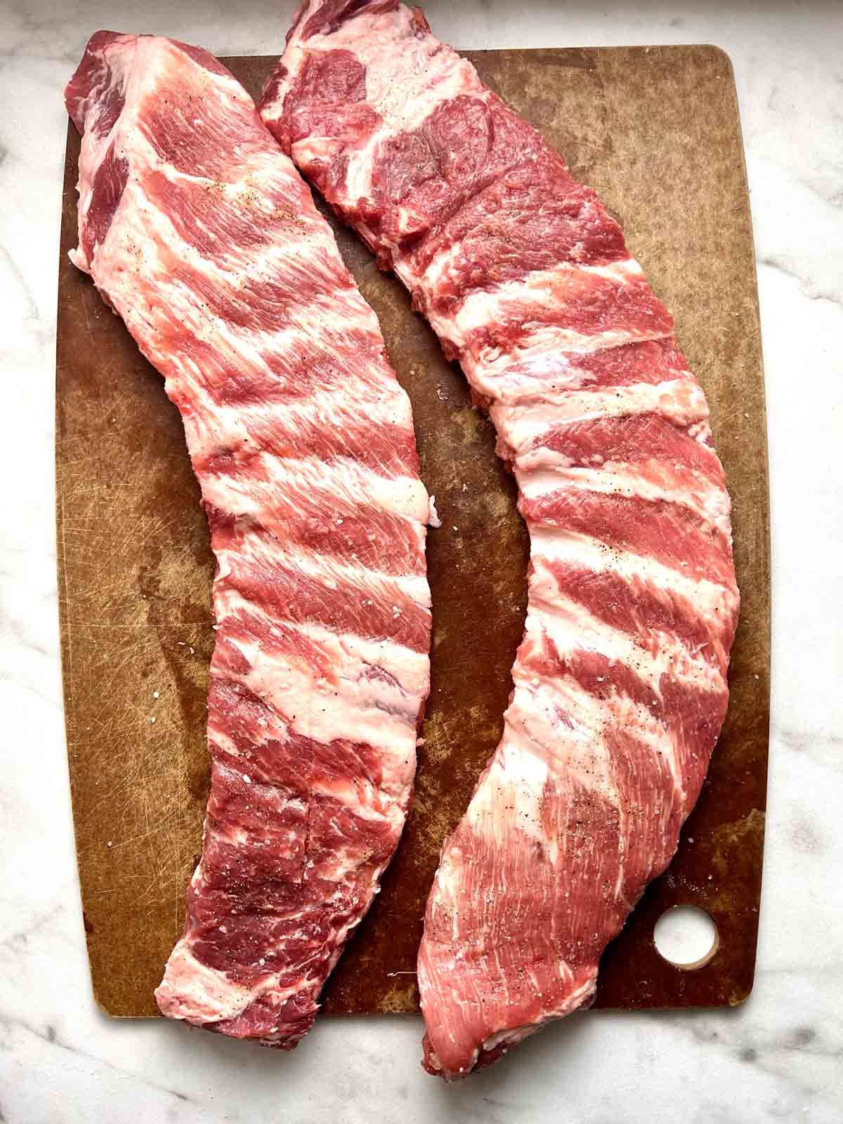 ribs being seasoned with salt and pepper.