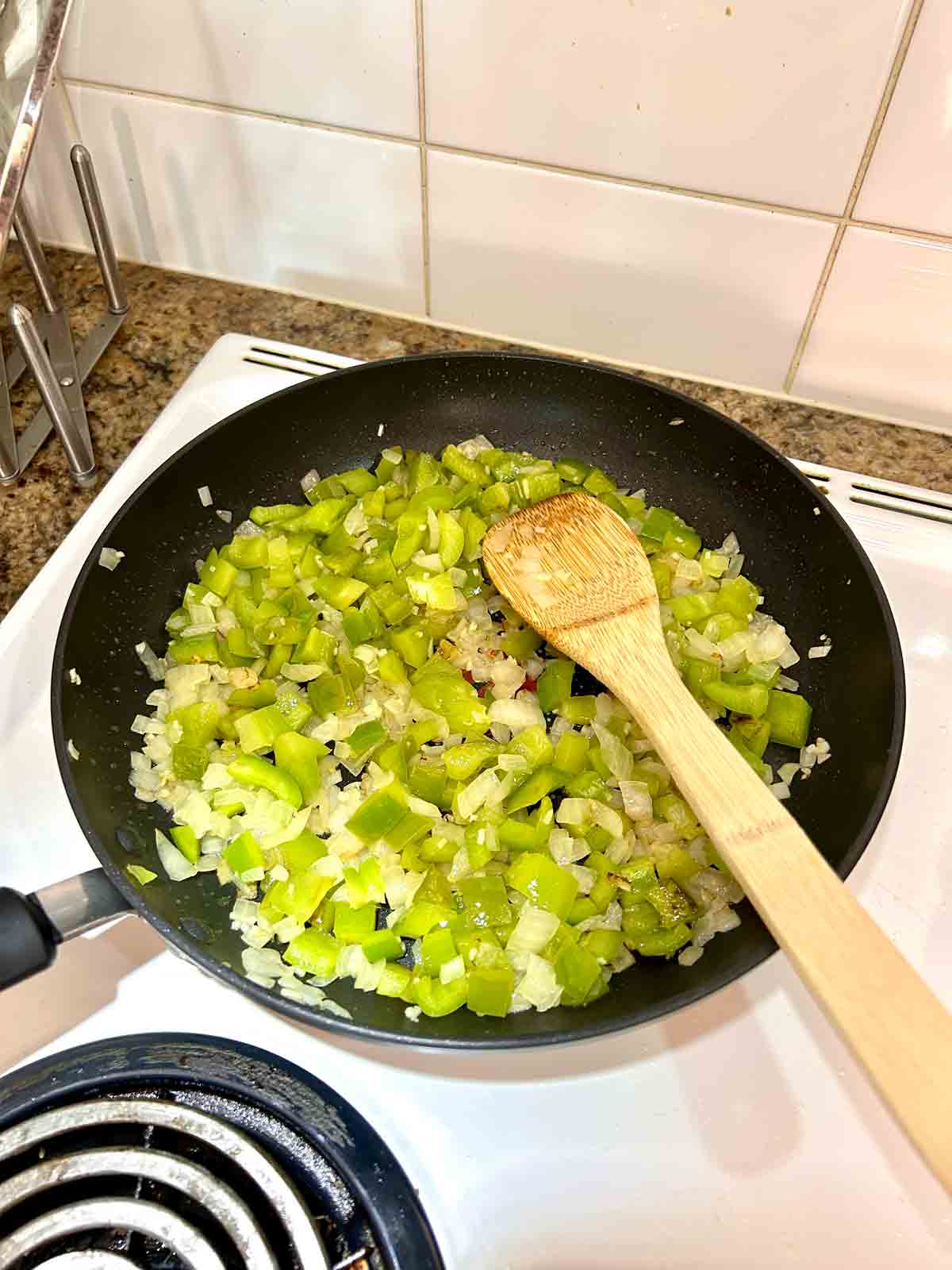 green bell pepper, onion, and garlic sautรฉed in pan.