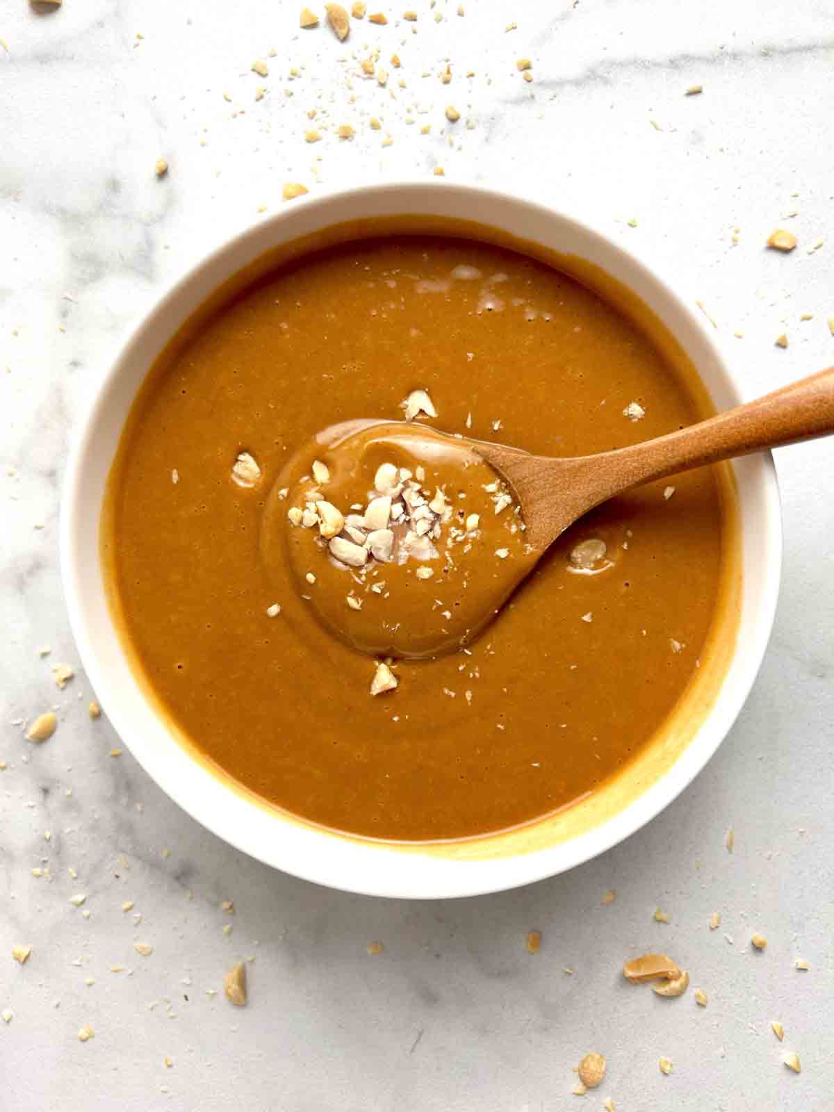 bowl of peanut sauce with chopped peanuts sprinkled on top.