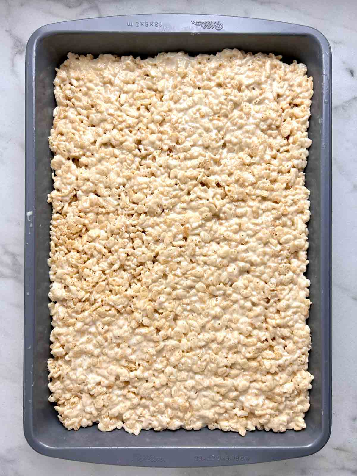 Rice Krispies mixture flattened in baking dish.