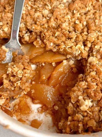 close up of spoon scooping some apple crisp in baking dish.