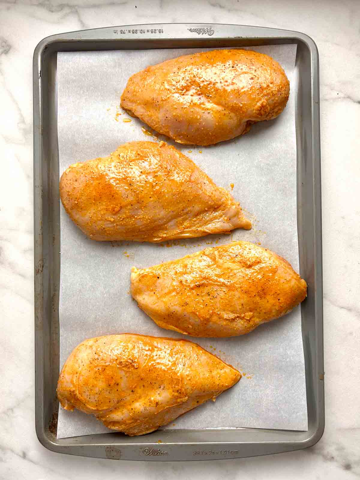 chicken breasts arranged on baking sheet.