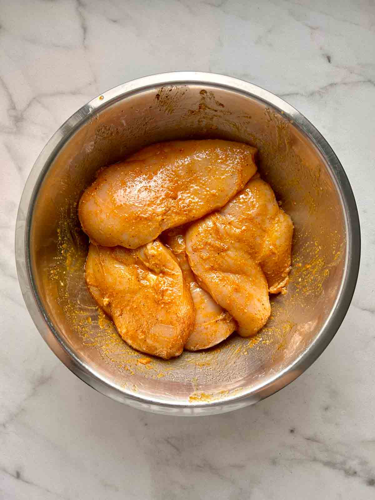 chicken being marinated in bowl.