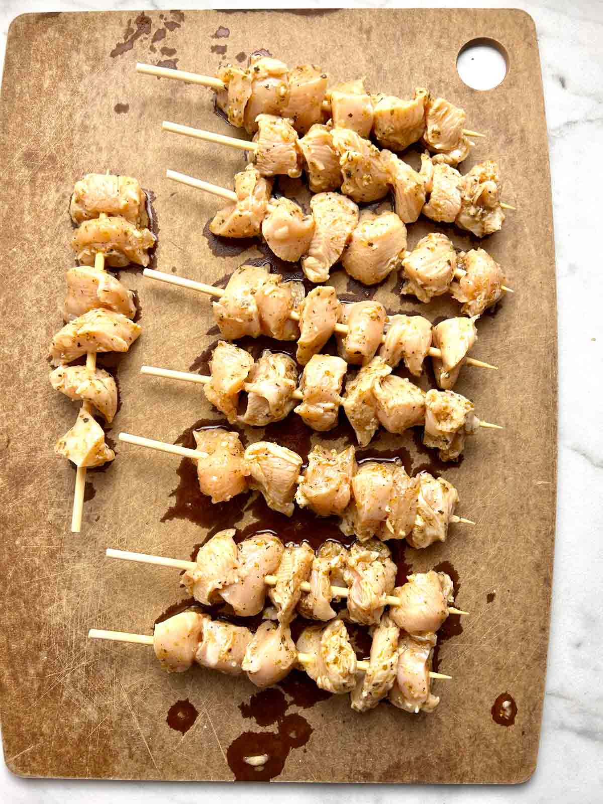 chicken being threaded onto skewers.