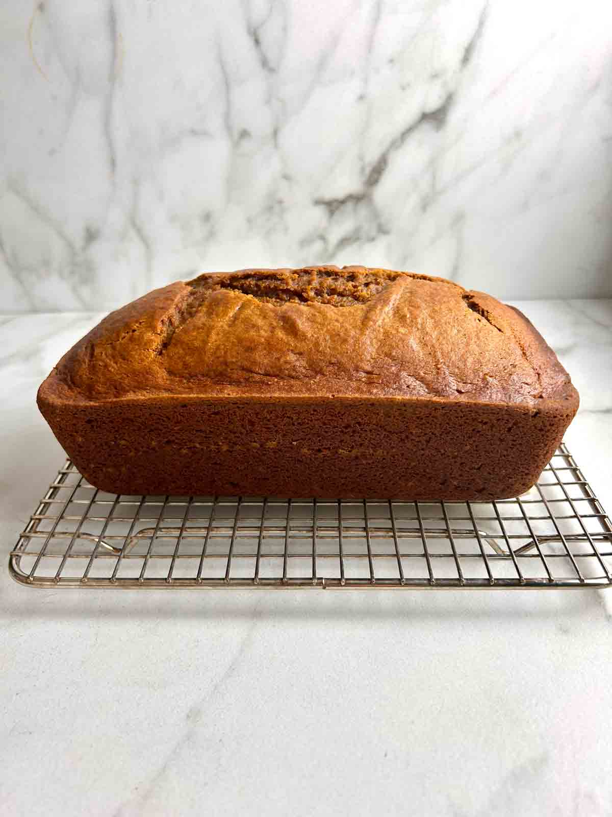 pumpkin bread resting on wire rack.