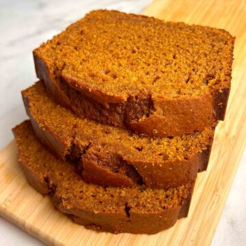 close up of 3 slices of pumpkin bread on wooden board.