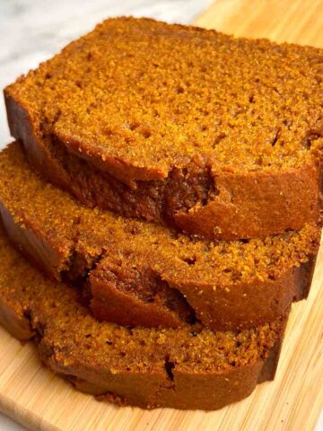close up of 3 slices of pumpkin bread on wooden board.