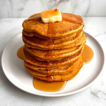 close up of stack of pumpkin pancakes with syrup drizzling over.