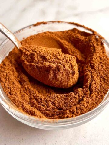 spoon lifting pumpkin spice powder from bowl.