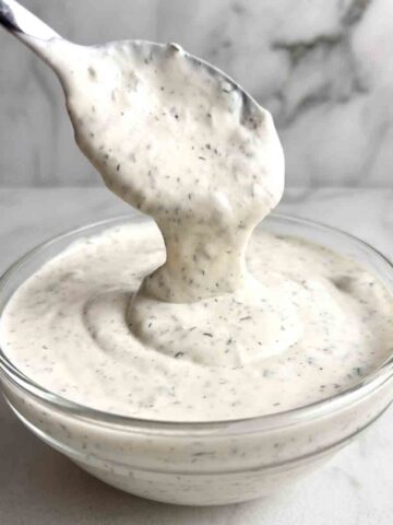 ranch dressing being lifted from bowl with spoon.