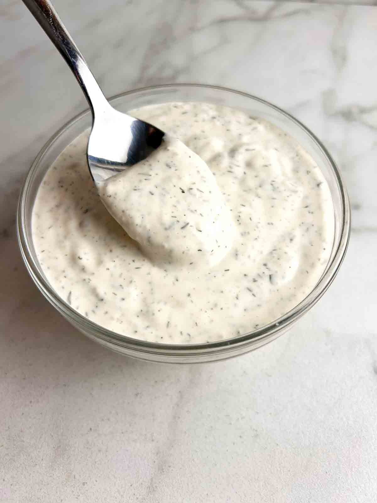 ranch dressing being lifted from bowl with spoon.