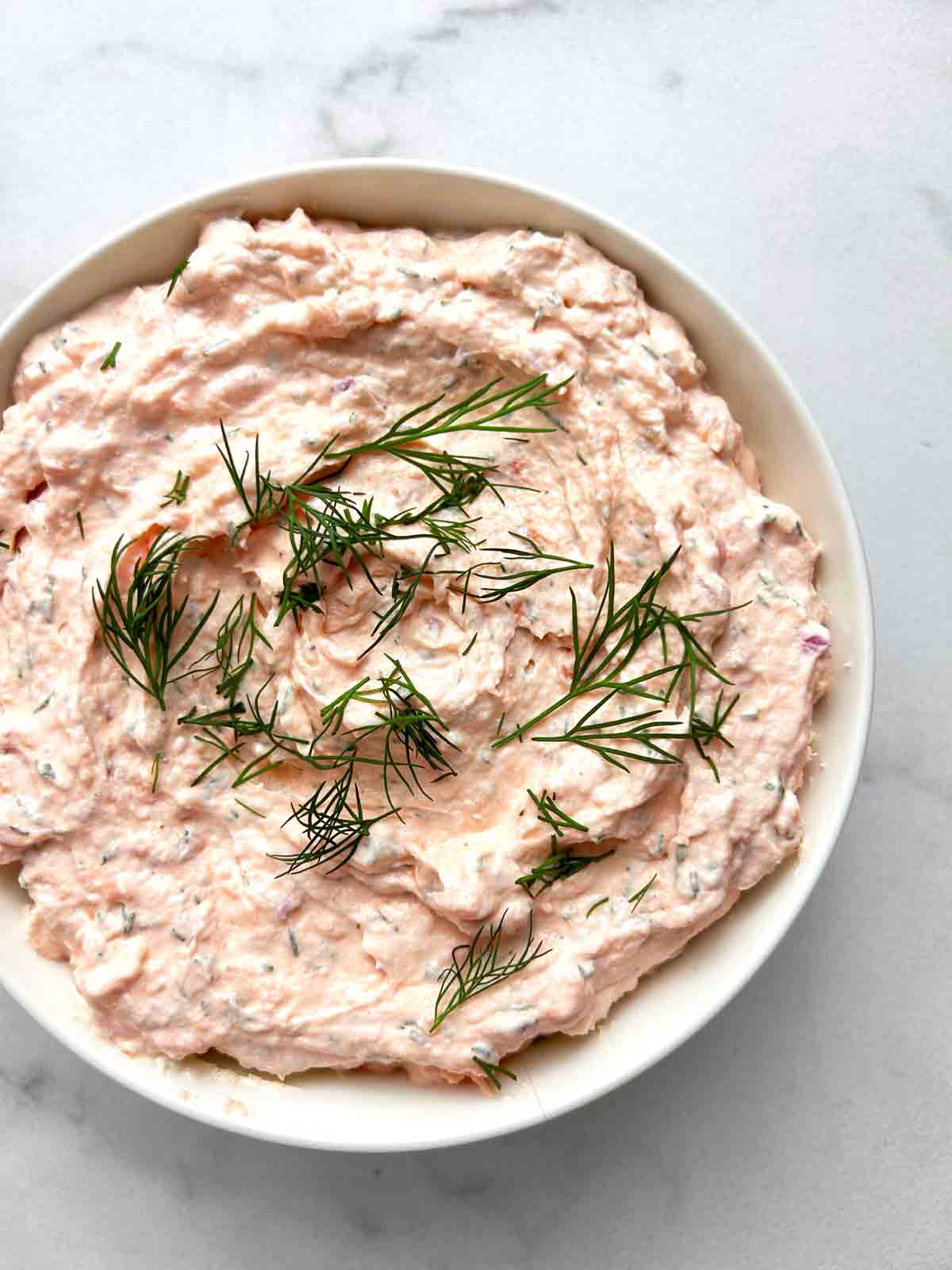 bowl of smoked salmon dip with dill fronds garnished on top.