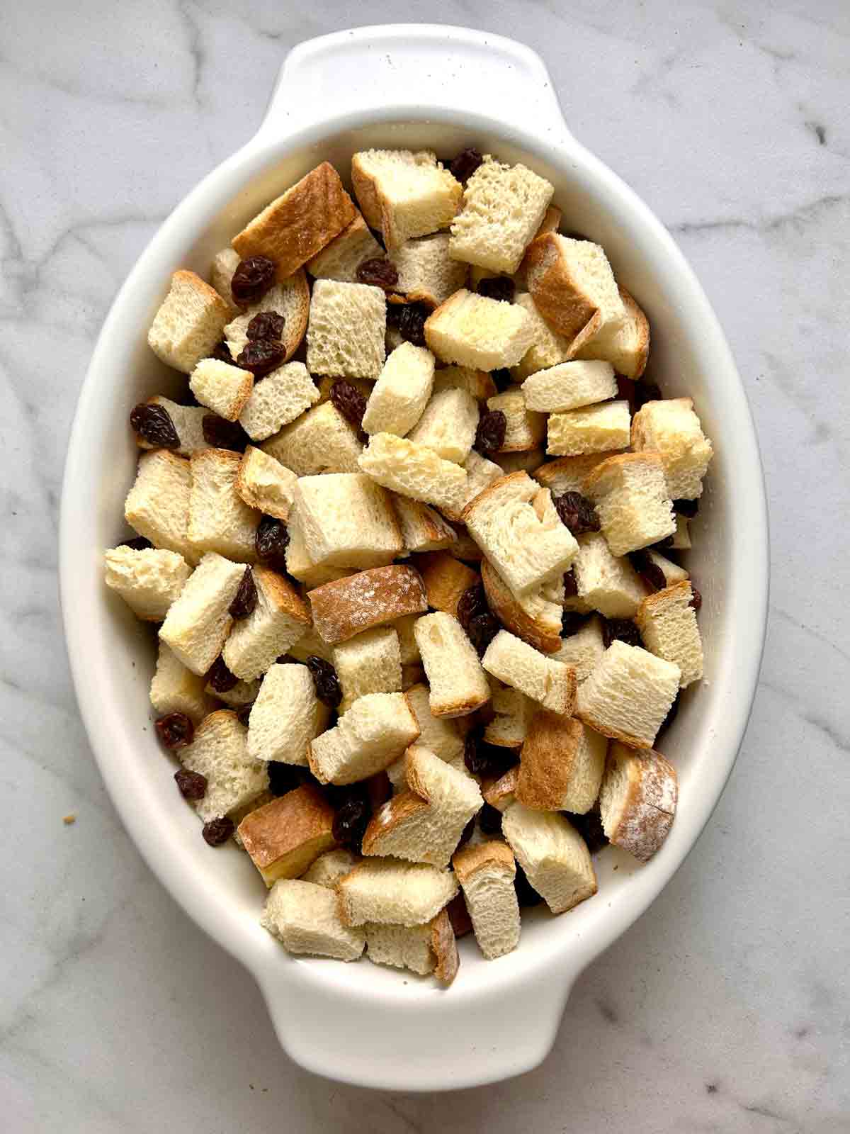 bread cubes and raisins added to baking dish.
