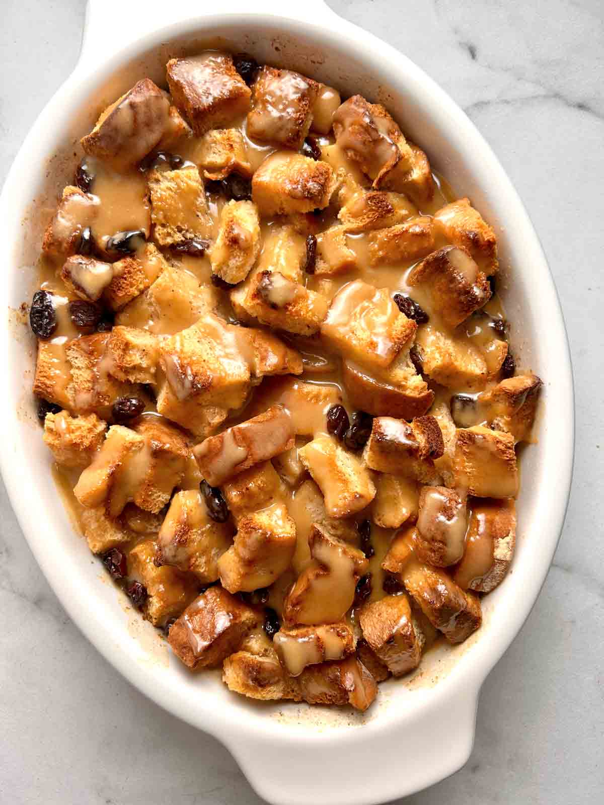 bread pudding with vanilla sauce drizzled over it.